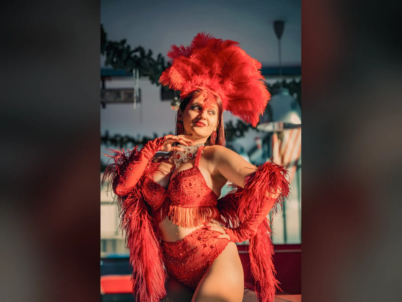 Ancilla Lilla in costume di scena rosso con copricapo di piume, insegnante del corso di burlesque AmaTease